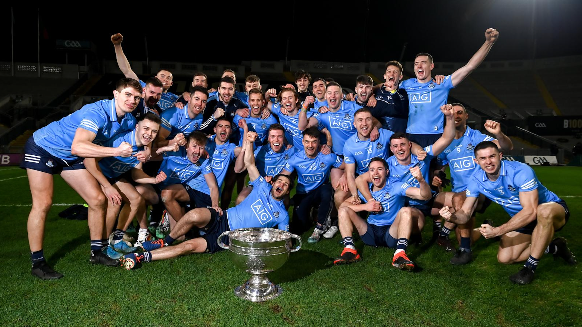 Dublin footballers in sky blue celebrating around the Sam Maguire Cup